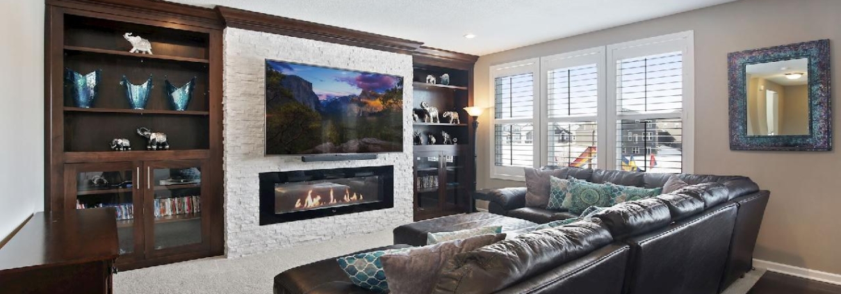 finished basement with stone fireplace dark wood cabinetry - Barefoot Construction Home Remodeling