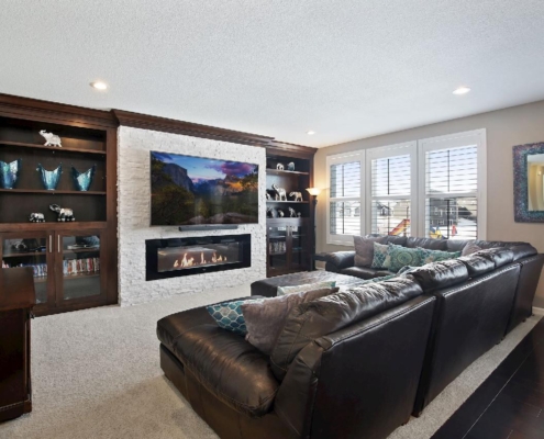 finished basement with stone fireplace dark wood cabinetry - Barefoot Construction Home Remodeling