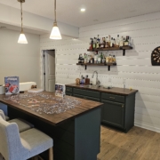finished basement with white shiplap walls and dark green cabinetry - Barefoot Construction Deck Construction, Basement Finishings and Home Additions