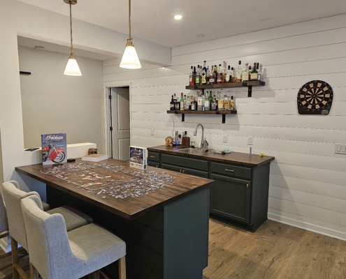 finished basement with white shiplap walls and dark green cabinetry - Barefoot Construction Deck Construction, Basement Finishings and Home Additions