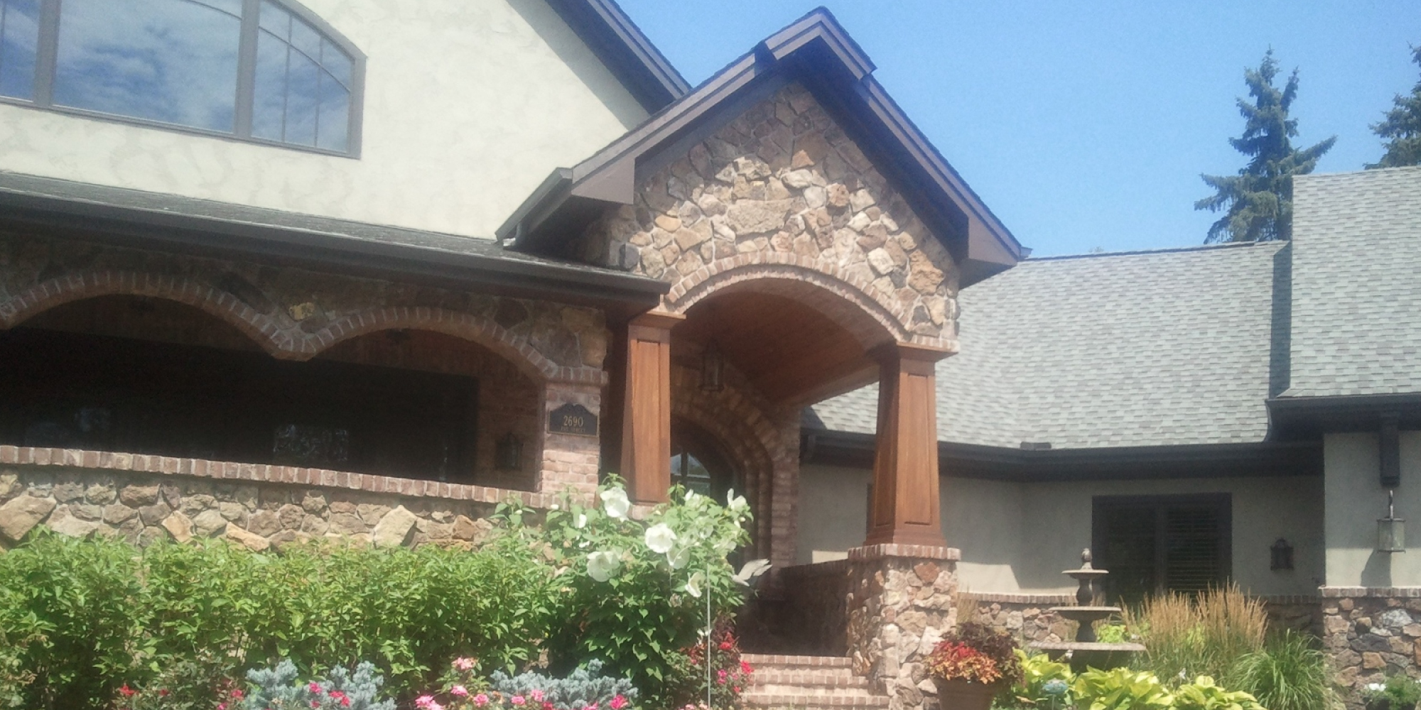 home exterior with a stone arch and wood posts - Barefoot Construction Deck Construction, Basement Finishings and Home Additions