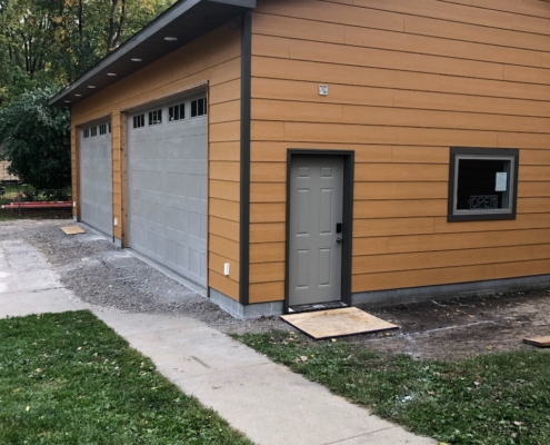 new wood siding and grey garage doors - Barefoot Construction Deck Construction, Basement Finishings and Home Additions