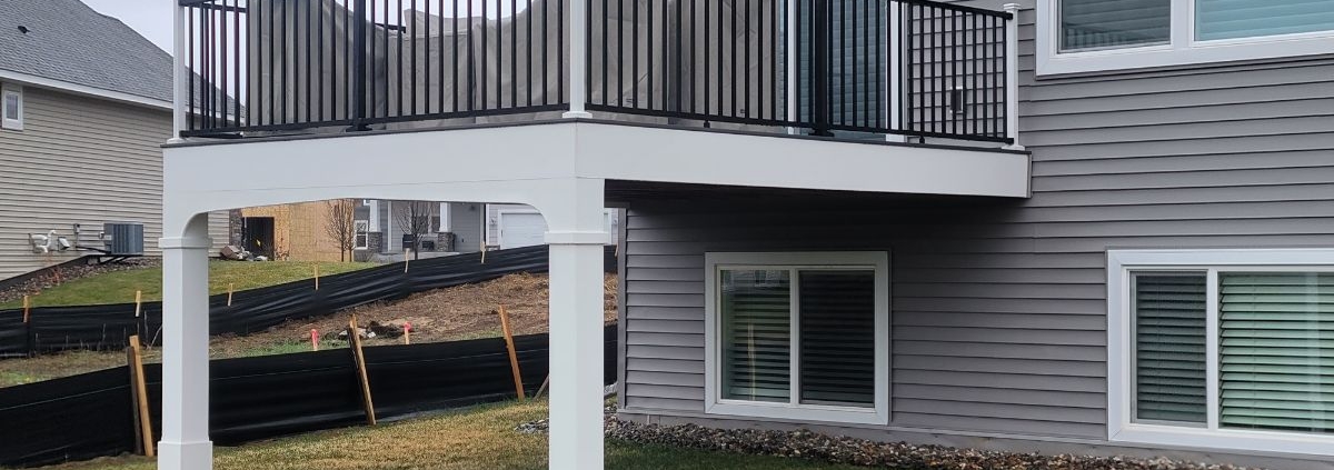 new white and black deck attached to grey house - Barefoot Construction deck builders near