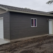 newly built home addition with a white door and dark grey siding - Barefoot Construction home addition