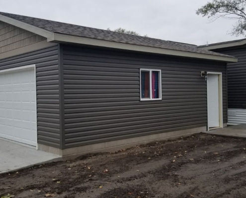 newly built home addition with a white door and dark grey siding - Barefoot Construction home addition