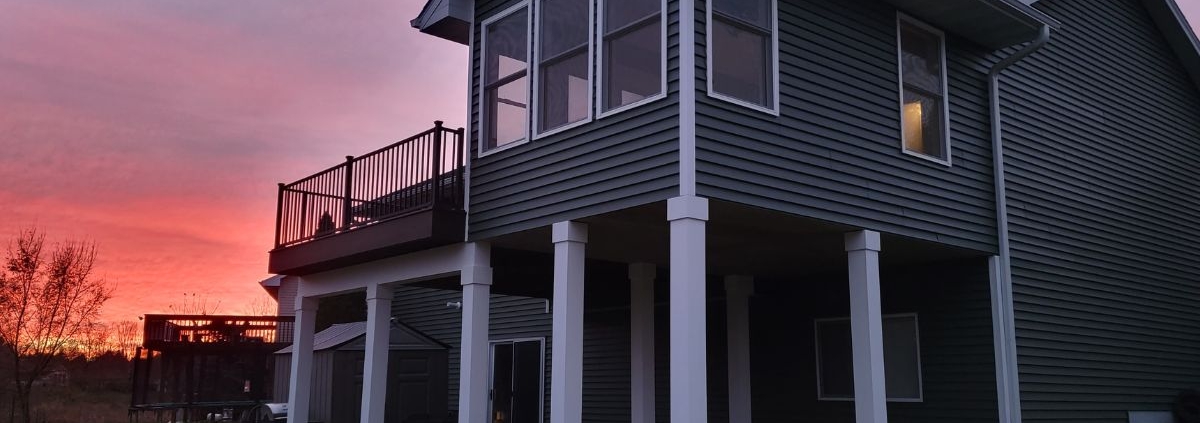 home addition with grey siding and white posts - Barefoot Construction home addition