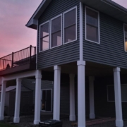 home addition with grey siding and white posts - Barefoot Construction home addition