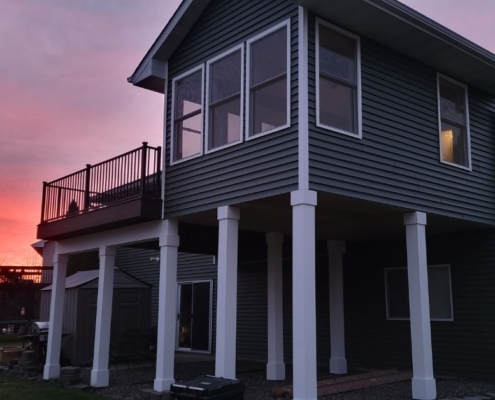 home addition with grey siding and white posts - Barefoot Construction home addition