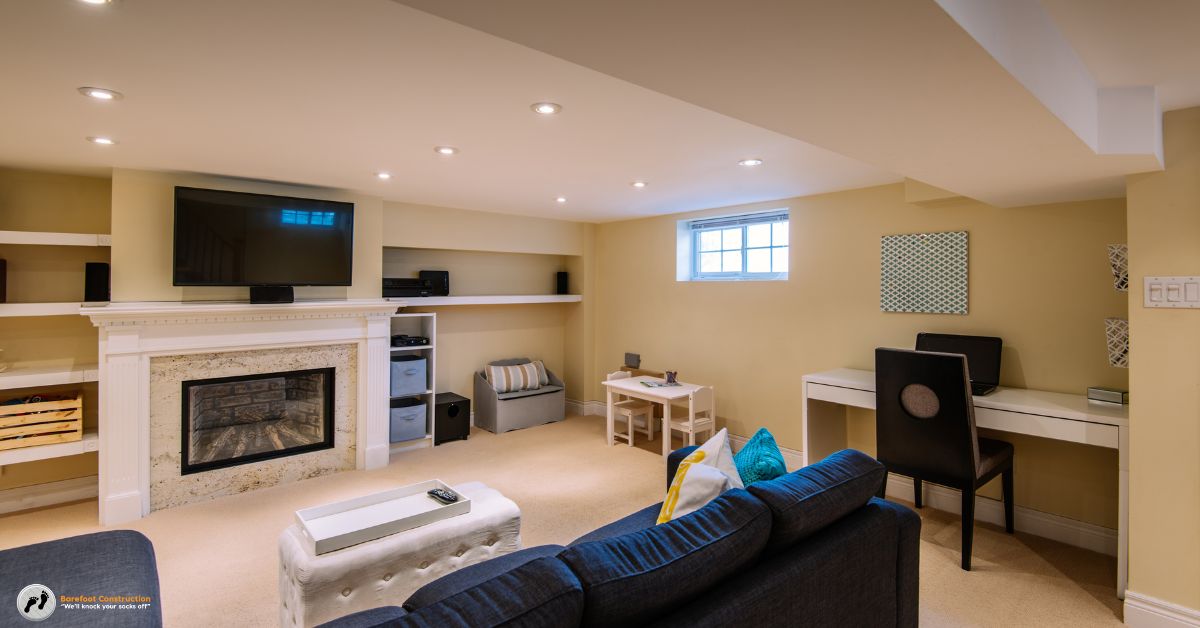 finished basement with a fireplace and blue couch - Barefoot Construction basement finishing