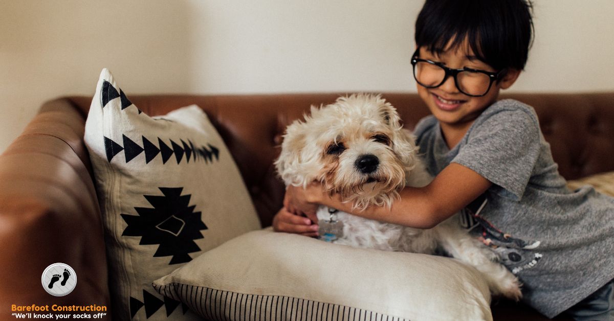 child wearing glasses hugging their white dog - Barefoot Construction basement remodel