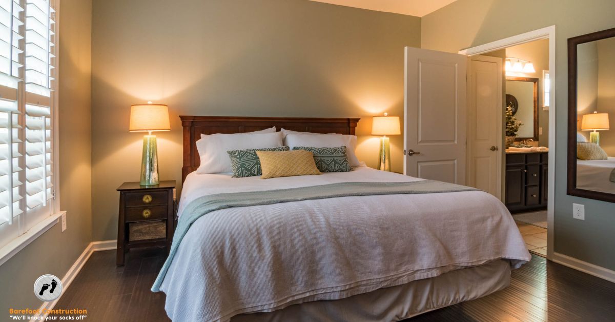 large bed with a white comforter and dimmed lamps - Barefoot Construction basement remodel