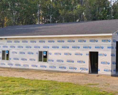 home addition with plastic wrap and a grey roof - Barefoot Construction home addition