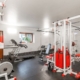 home gym located in the basement with white and red equipment - Barefoot Construction basement finishing