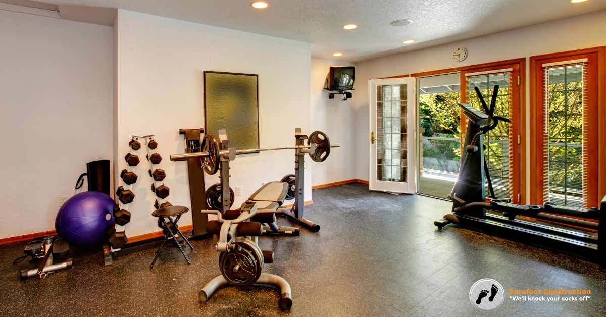 home gym located in the basement with white and red equipment - Barefoot Construction basement finishing