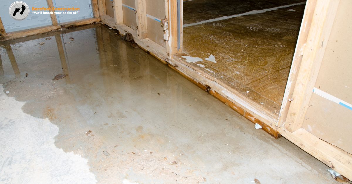 unfinished basement with water on the floor - Barefoot Construction basement finishing