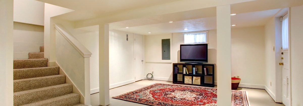 finished basement with a red rug and entertainment center - Barefoot Construction basement finishing