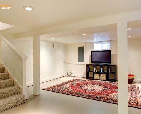 finished basement with a red rug and entertainment center - Barefoot Construction basement finishing