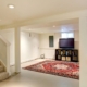 finished basement with a red rug and entertainment center - Barefoot Construction basement finishing