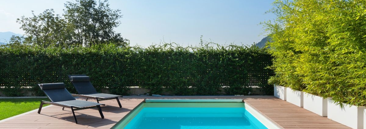 blue pool surrounded by deck boards and chairs - Barefoot Construction composite decking