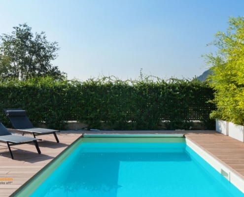 blue pool surrounded by deck boards and chairs - Barefoot Construction composite decking