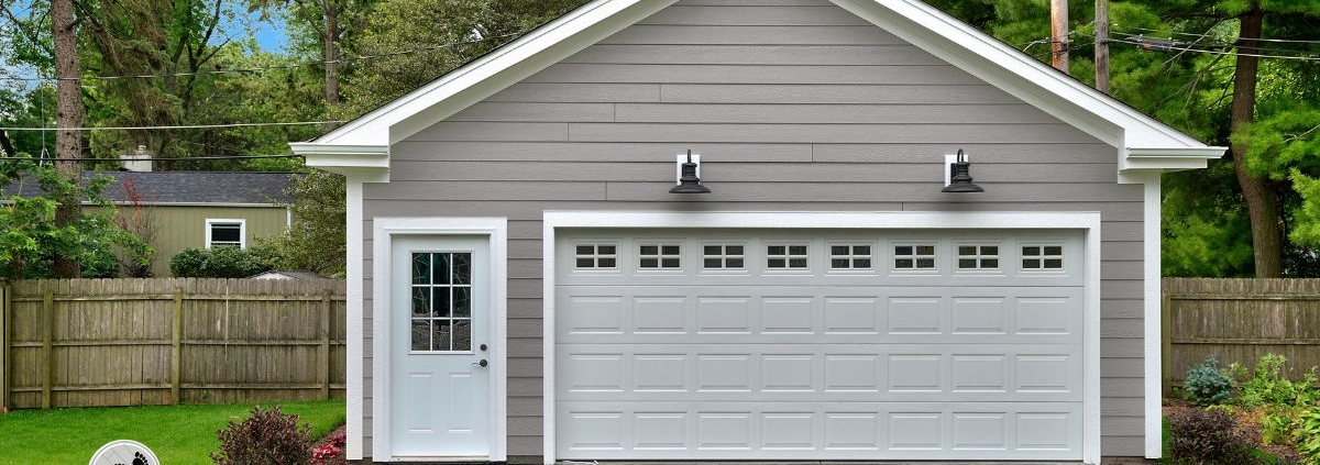 detached garage with white door and grey vinyl siding - Barefoot Construction garage addition