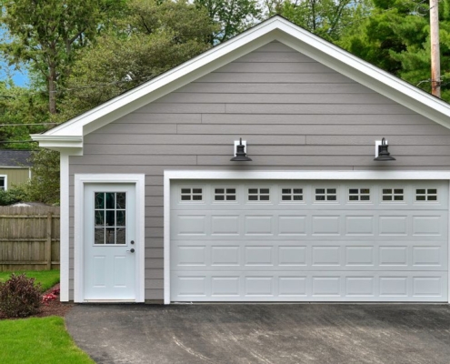 detached garage with white door and grey vinyl siding - Barefoot Construction garage addition