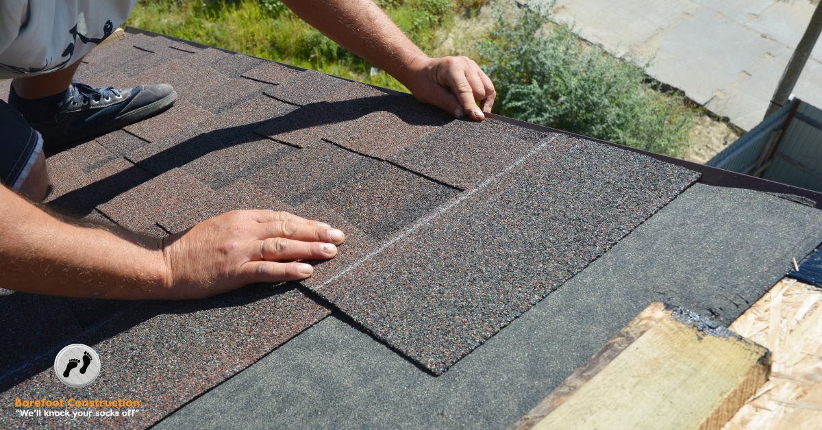 person laying new asphalt shingles on a roof - Barefoot Construction roof replacement