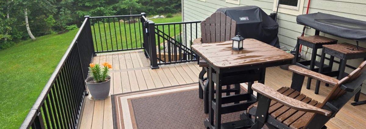 composite deck with patio furniture and a covered grill as well as flower pots - Barefoot Construction
