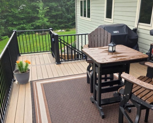composite deck with patio furniture and a covered grill as well as flower pots - Barefoot Construction