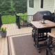 composite deck with patio furniture and a covered grill as well as flower pots - Barefoot Construction