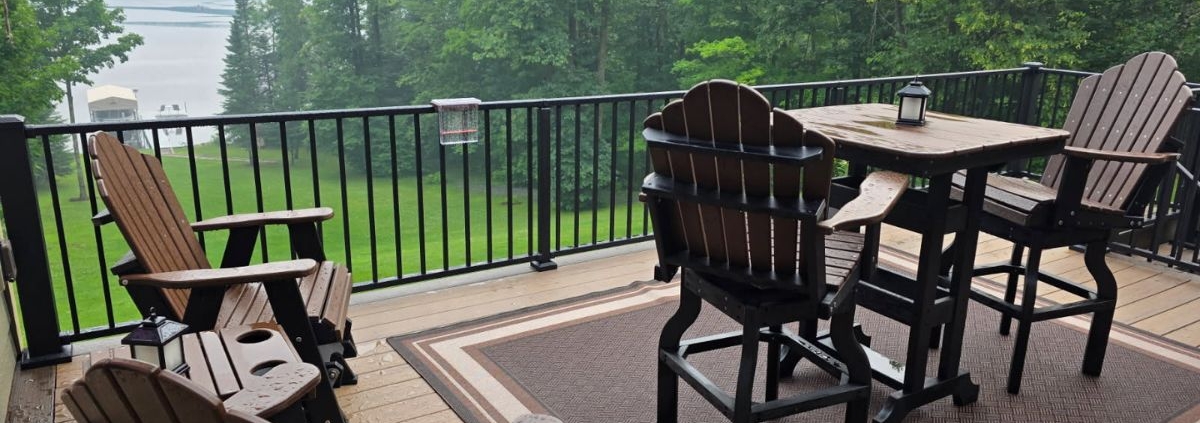 composite deck with patio furniture and a covered grill and a lake view - Barefoot Construction decking material cost comparison