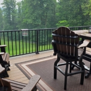 BarefootConstruction-happy-client-July-2025-3 composite deck with patio furniture and a covered grill and a lake view - Barefoot Construction decking material cost comparison