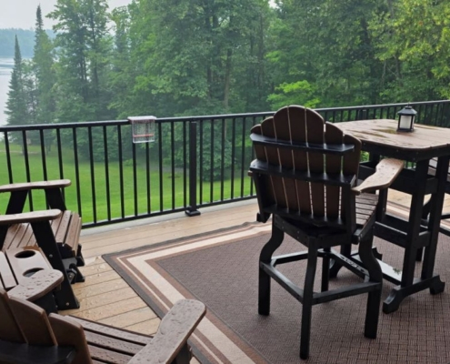 composite deck with patio furniture and a covered grill and a lake view - Barefoot Construction decking material cost comparison