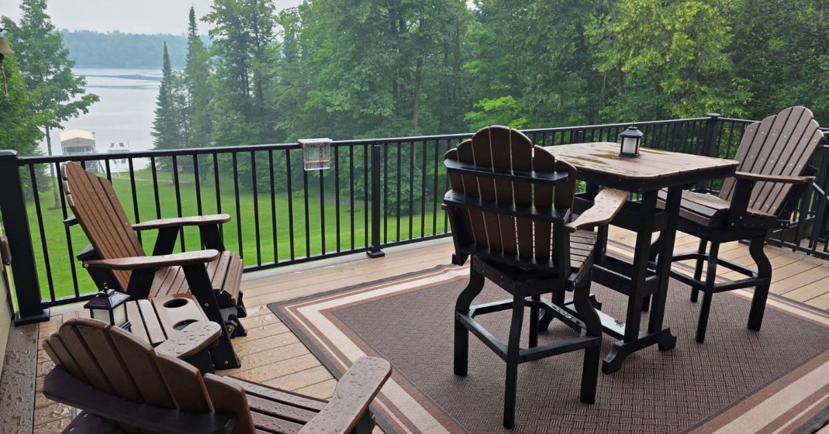 composite deck with patio furniture and a covered grill and a lake view - Barefoot Construction decking material cost comparison