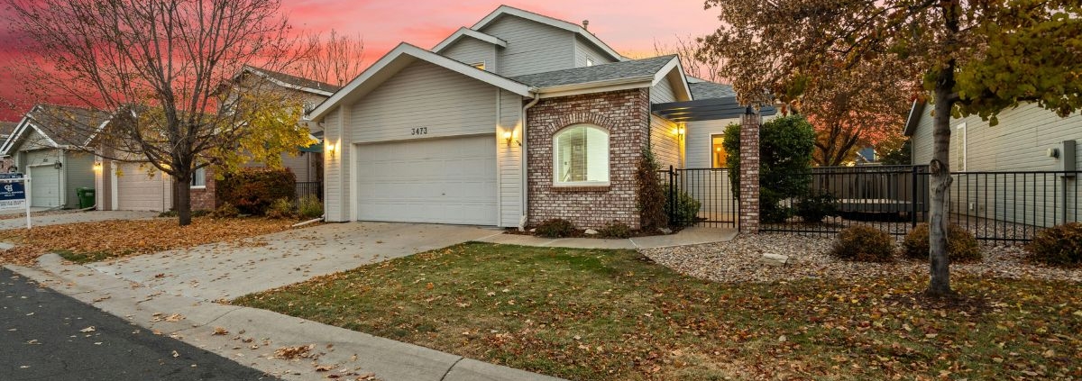 suburban home with bare trees and leaves on the grass - Barefoot Construction home remodeling