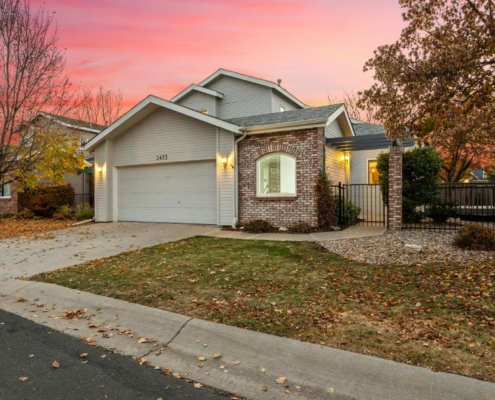 suburban home with bare trees and leaves on the grass - Barefoot Construction home remodeling