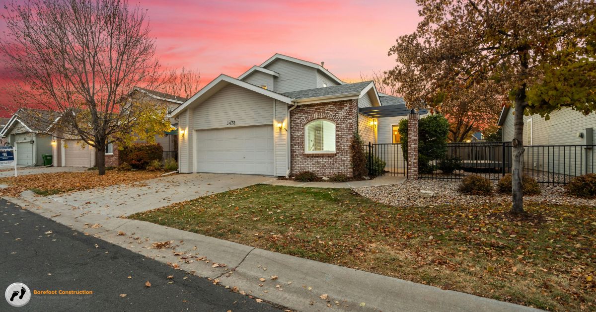 suburban home with bare trees and leaves on the grass - Barefoot Construction home remodeling